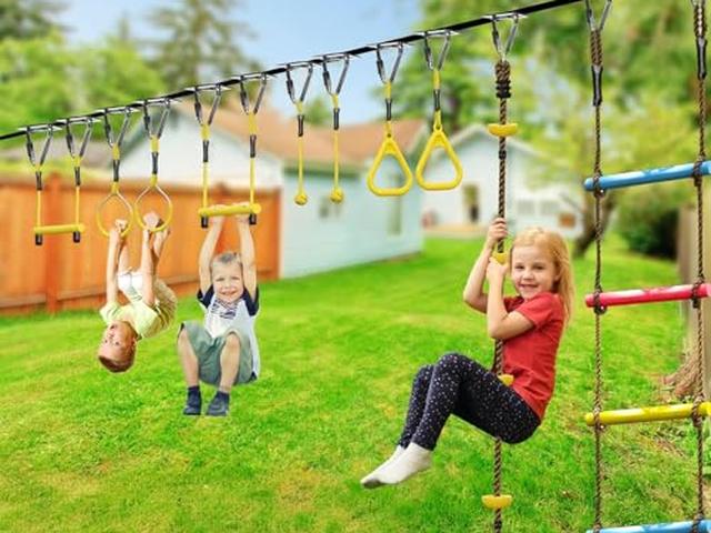 Children hanging from a ninja line strung across a garden lawn